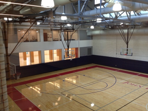 The basketball coaches offices have glass windows overlooking the court.